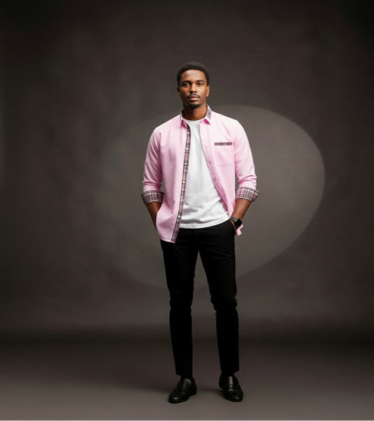 Man wearing a pink shirt over a white t-shirt with black pants on a dark background